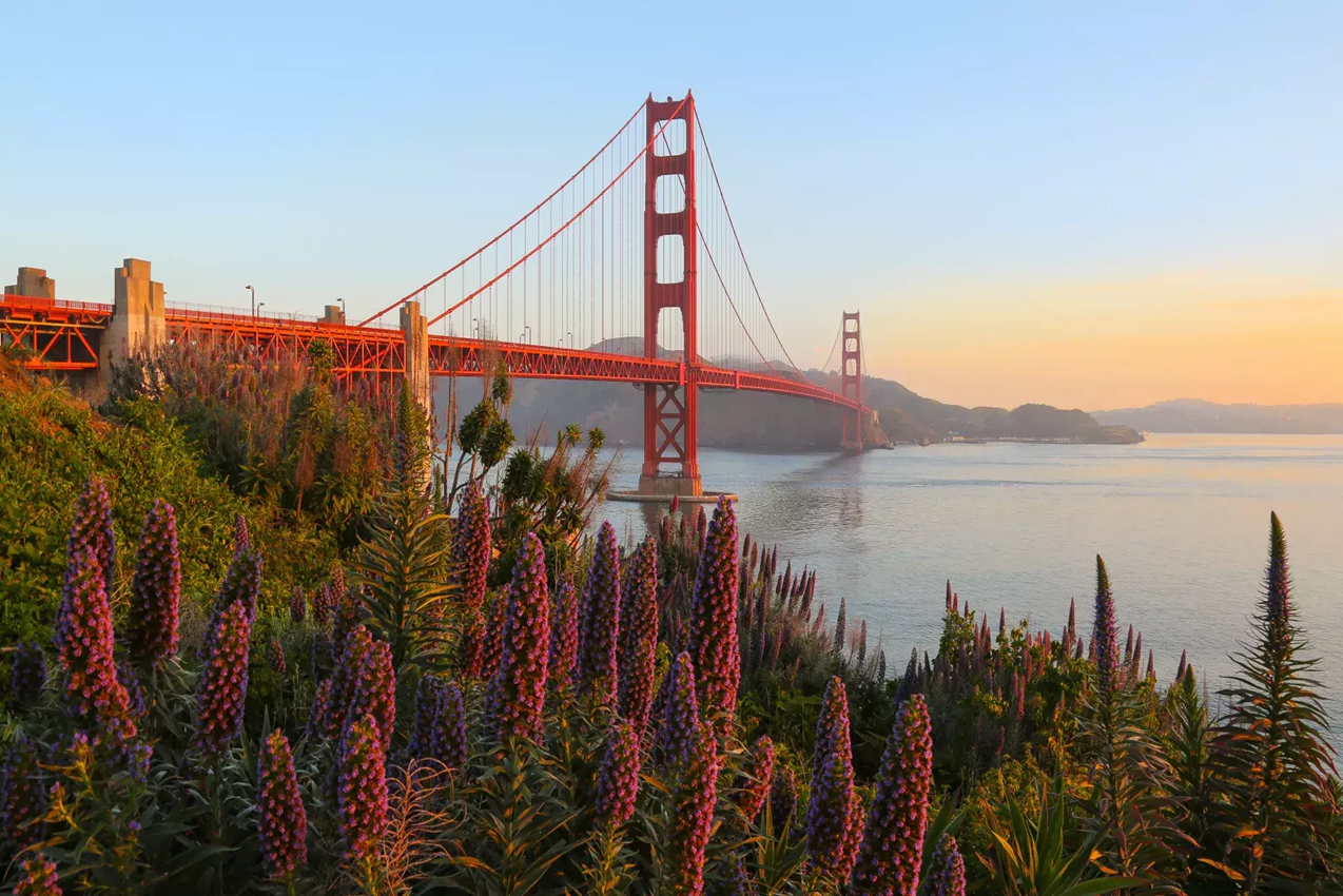 The Golden Gate Bridge shrouded in morning fog with the city skyline in the background the best places to travel in June .